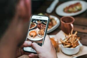 customer taking photo of restaurant food showing social media driven dining trends